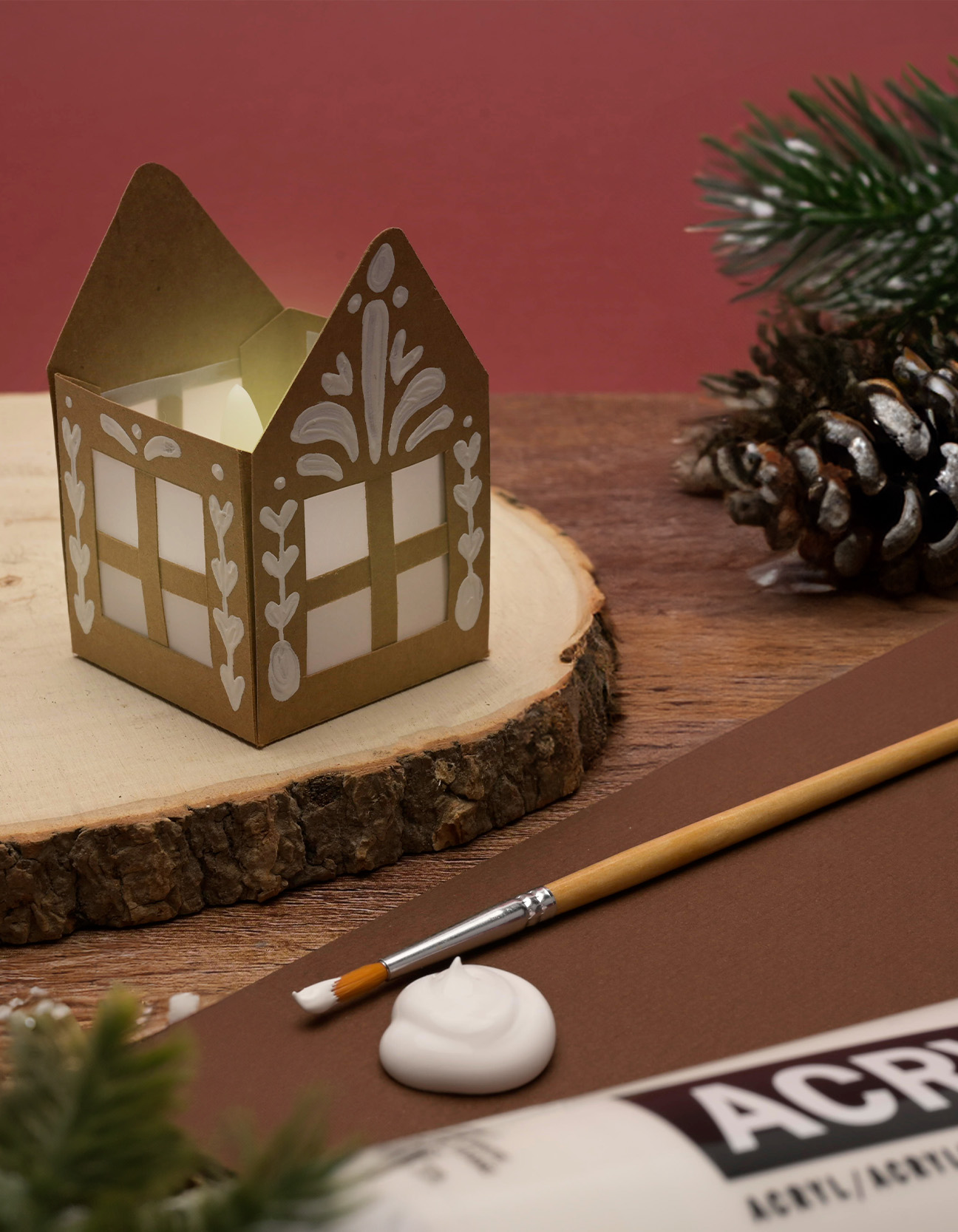 Farolito casero de papel con diseño de casita de jengibre, decorado con pintura acrílica blanca como proyecto navideño creativo.