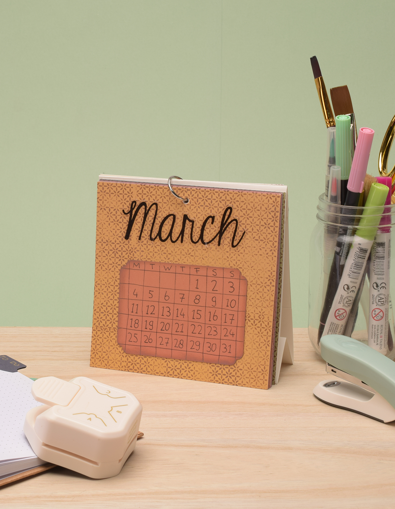 Le calendrier DIY terminé exposé sur un bureau avec des fournitures de bureau colorées.