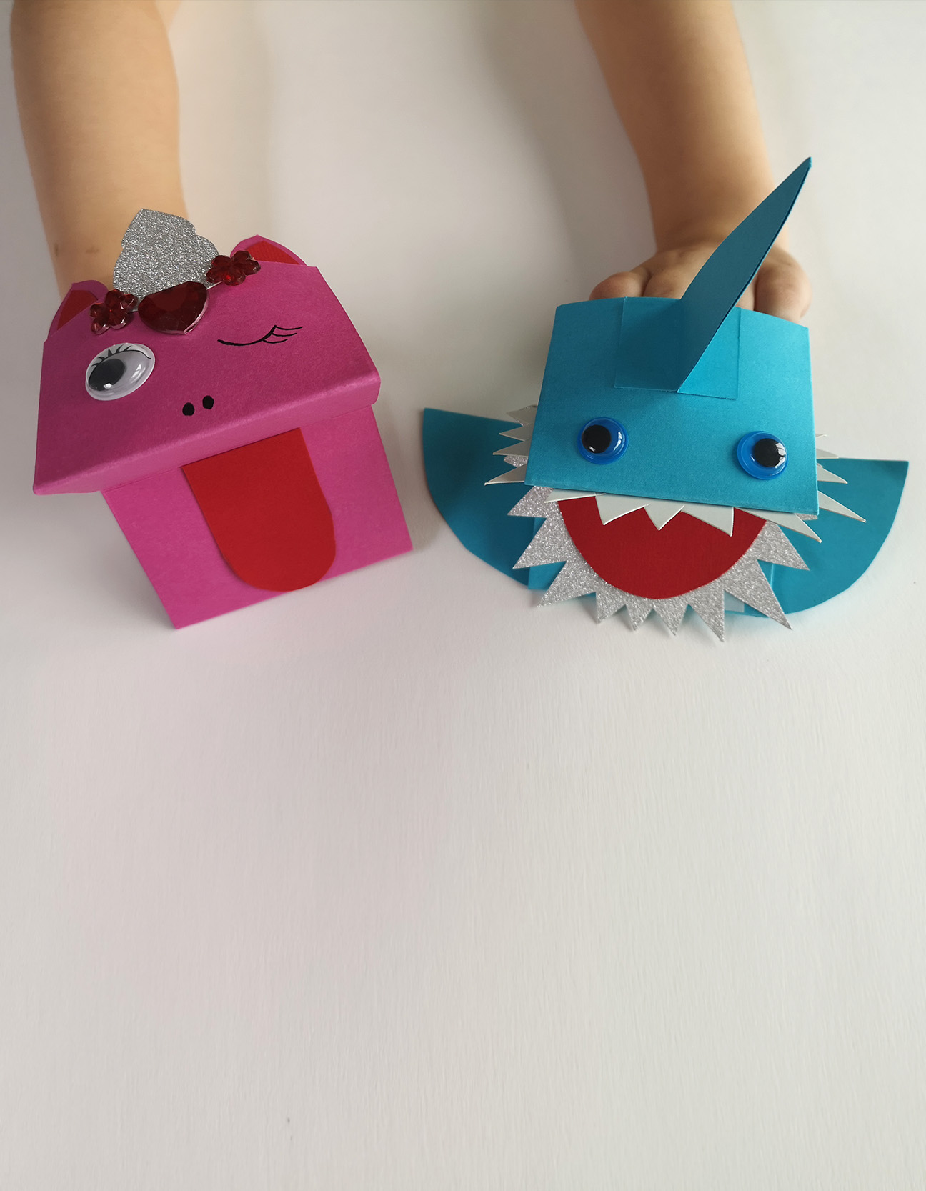 Afgewerkte papieren handpoppen, eenhoorn en haai, bespeeld door kinderen