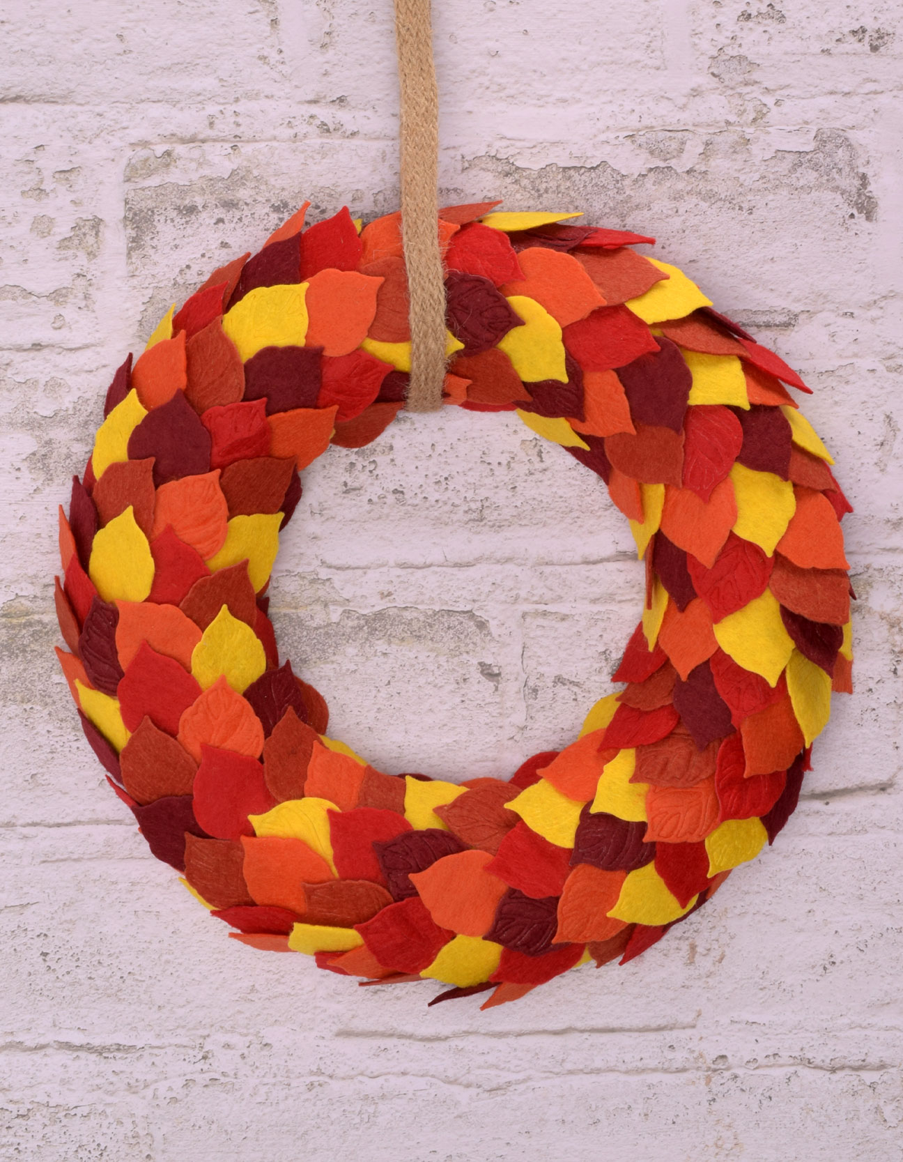 Afgewerkte herfstkrans van vilt met gelaagde blaadjes in rood, oranje en geel als sfeervolle herfstdecoratie.