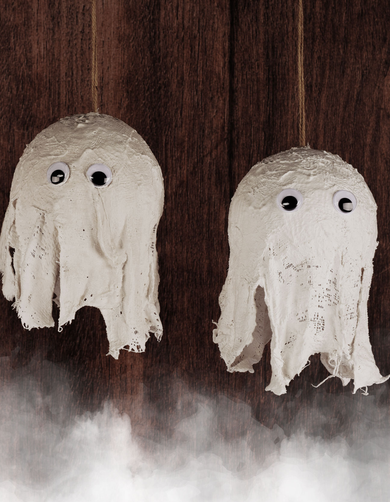 Zwei hängende Gipsgeister mit Wackelaugen als Halloween-Dekoration