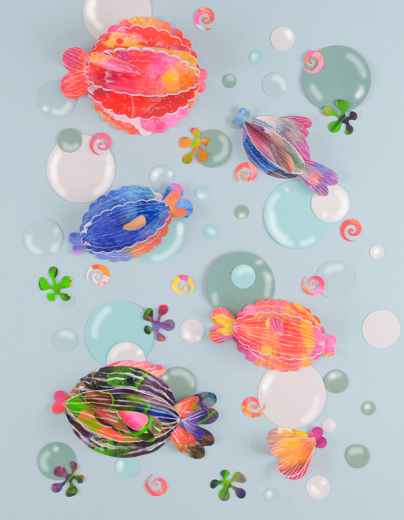 Obra creativa con peces de papel 3D coloridos, capas pintadas y efecto brillante estilo submarino.