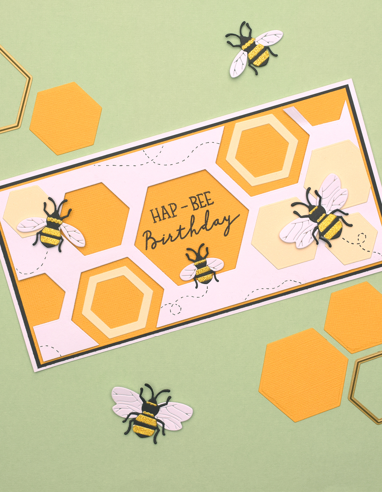 Tarjeta de cumpleaños terminada con diseño de panal hexagonal en capas y abejas decorativas con detalles dorados brillantes.