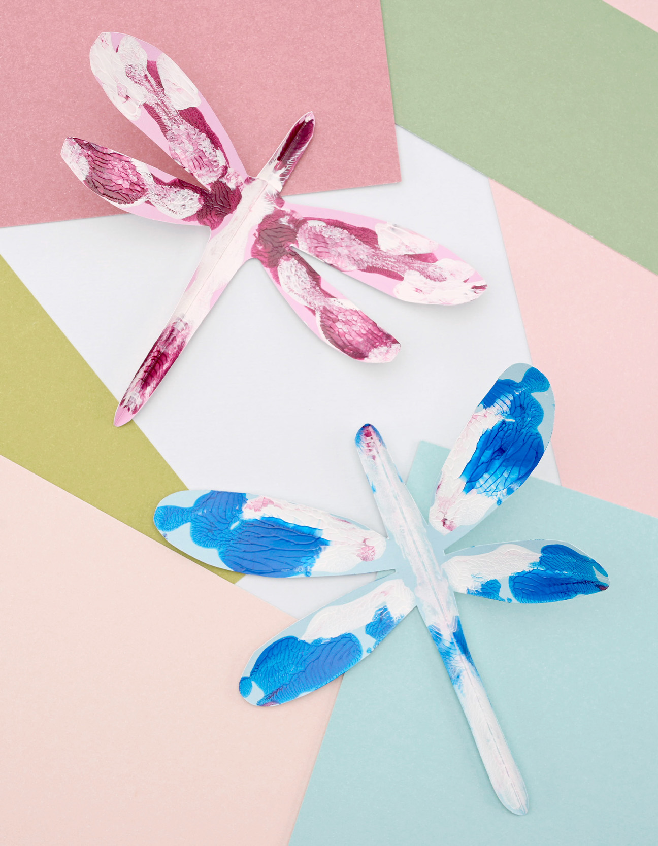 Libellule di carta finite in rosa e blu con effetto stampa su sfondo dai colori pastello