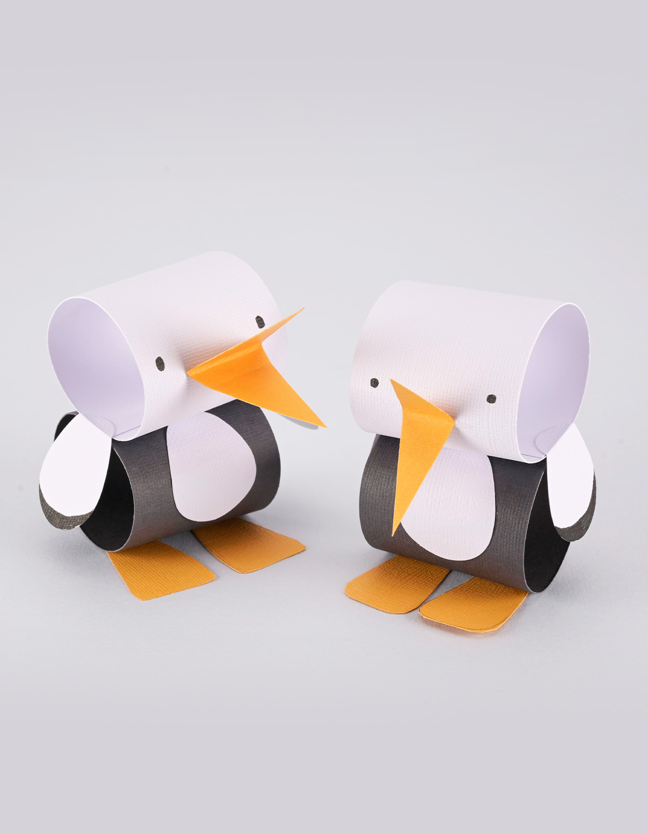 Two handmade paper storks made from white, black and orange cardstock, perfect as a cheerful DIY decoration.