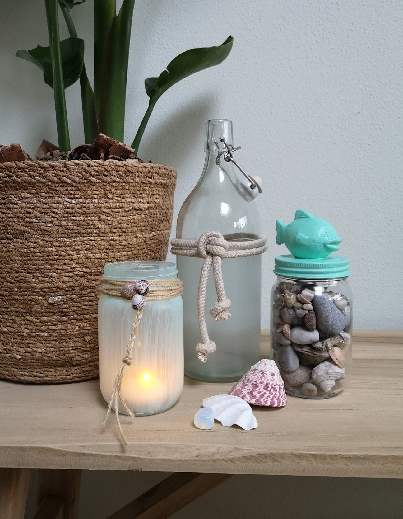 Barattoli sea glass finiti con conchiglie, sassi, juta e coperchio con pesciolino turchese per decorazioni estive.
