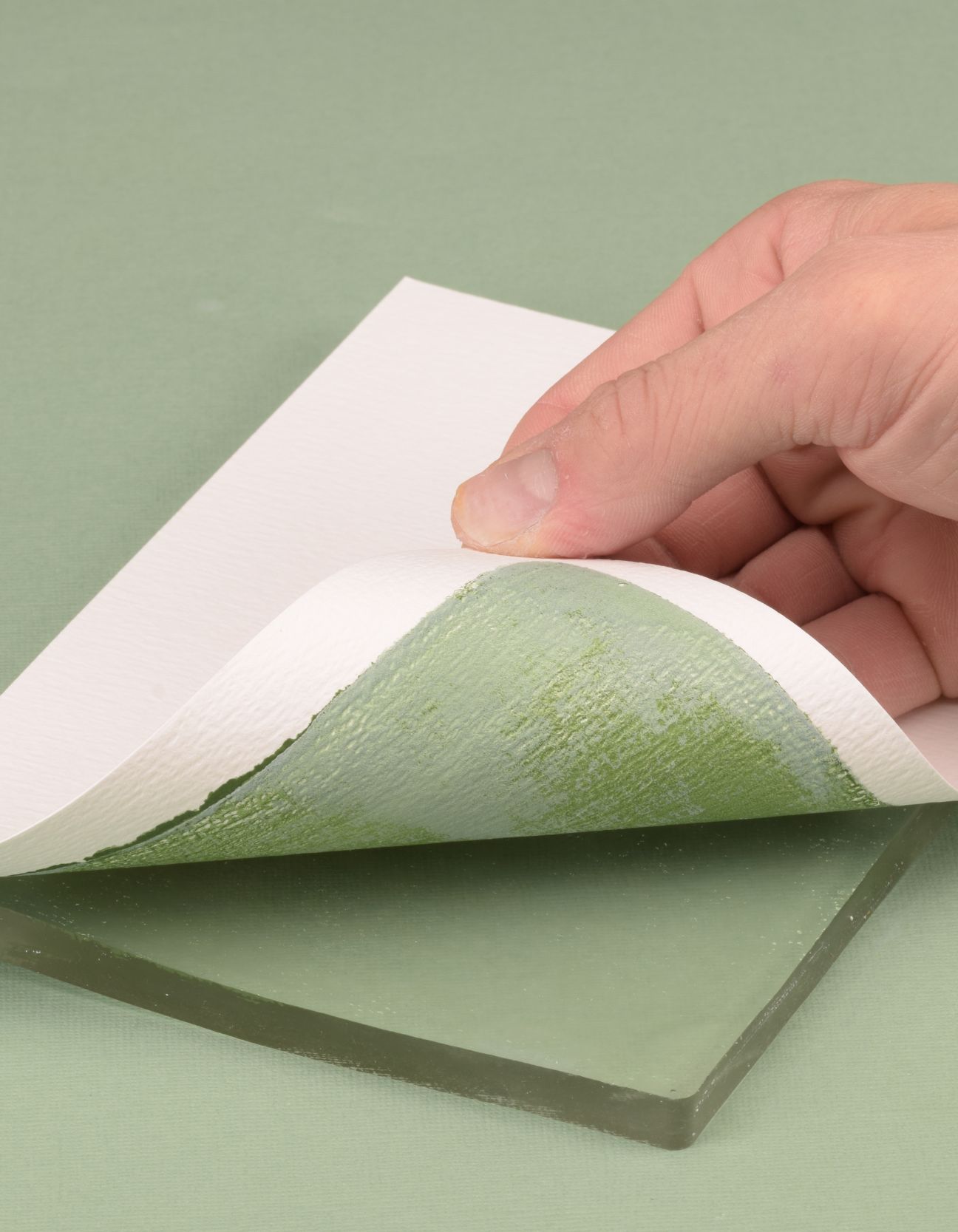 Lifting paper from a Gel Press plate to reveal a green gel printing background