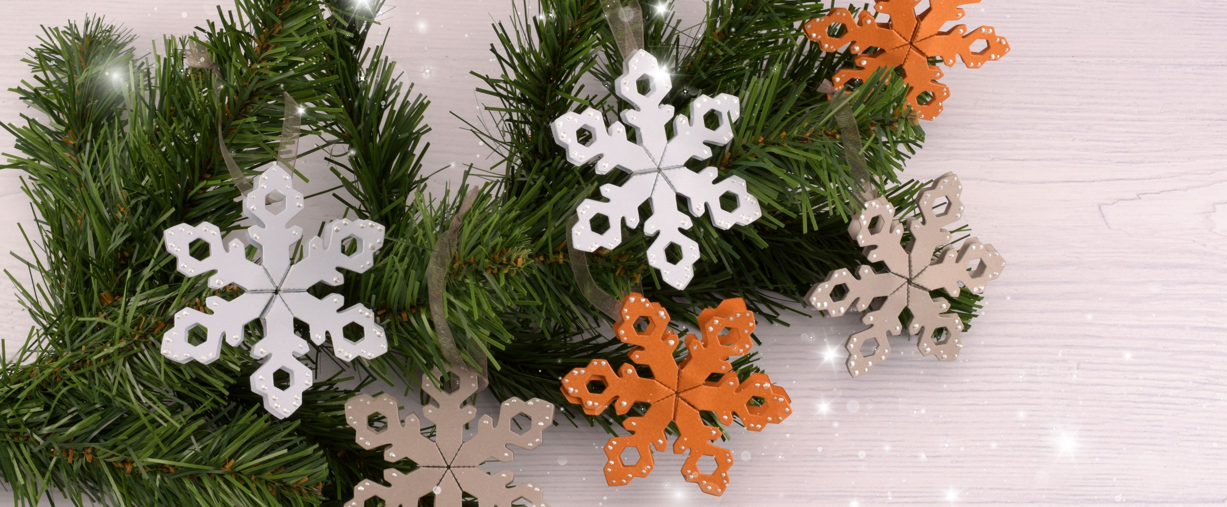 3D papieren sneeuwvlokken als kerstdecoratie, opgehangen in een groene dennentak