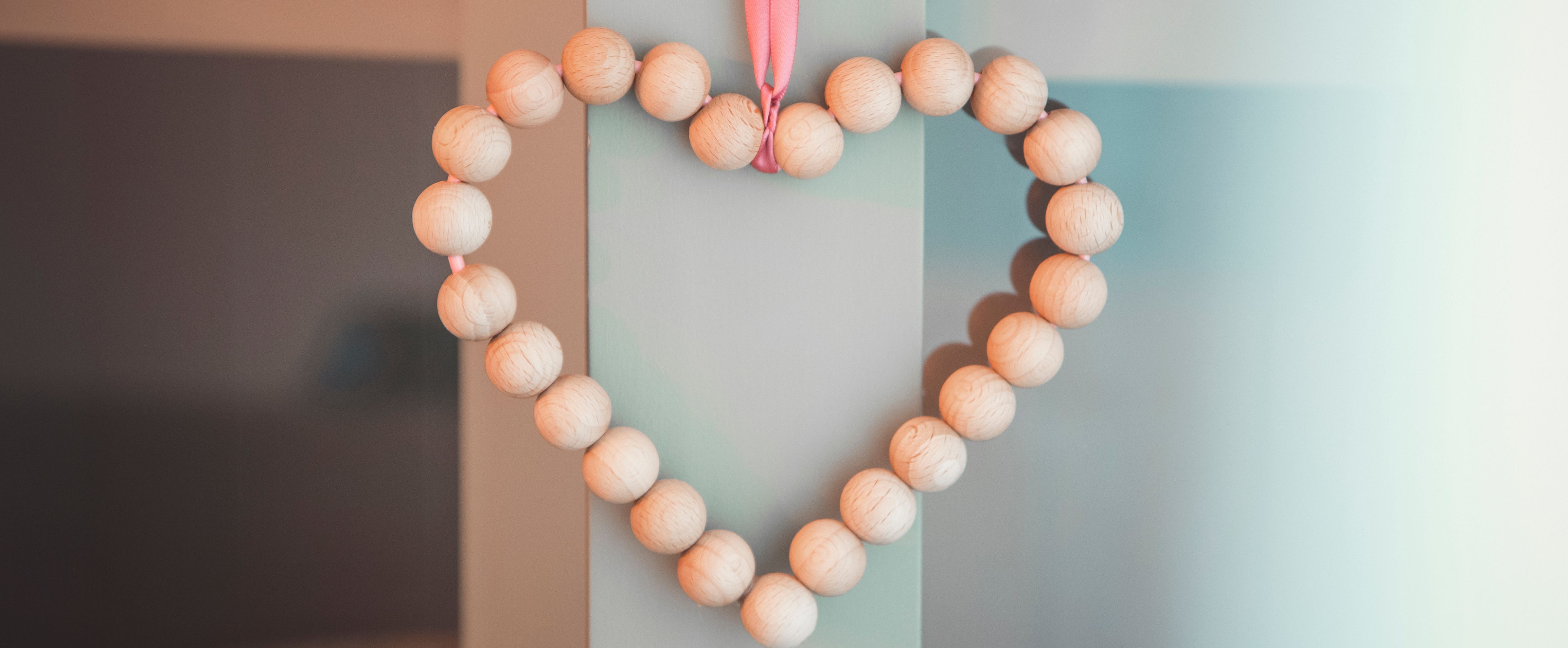 Suspension cœur en perles de bois avec ruban décoratif pour un DIY simple.