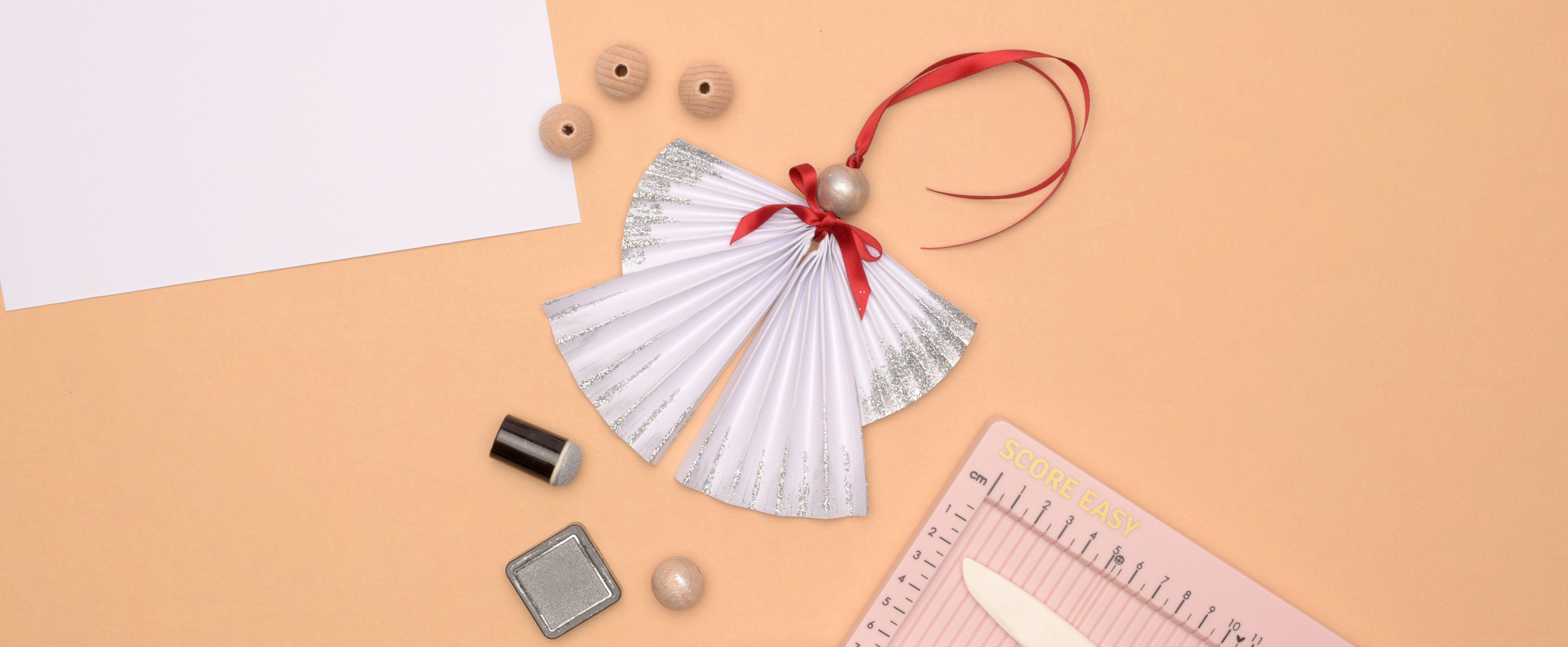 Decorazione natalizia a forma di angelo in carta piegata con glitter argento e nastro rosso.