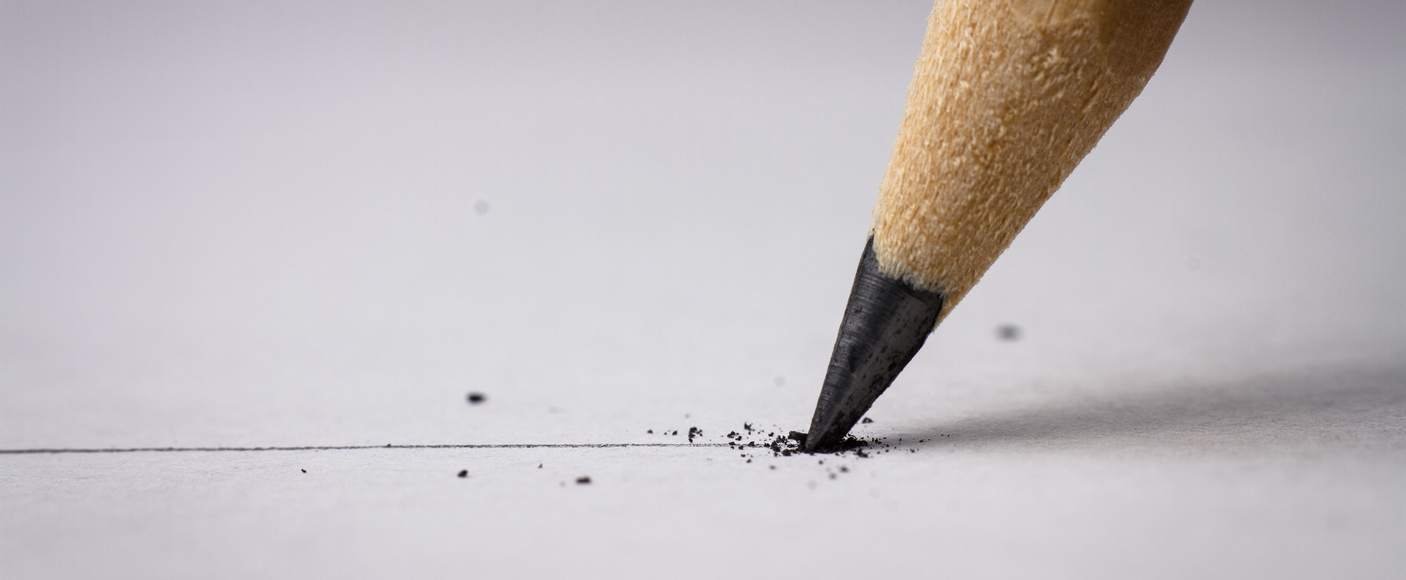 Close-up of a graphite pencil drawing a line on paper