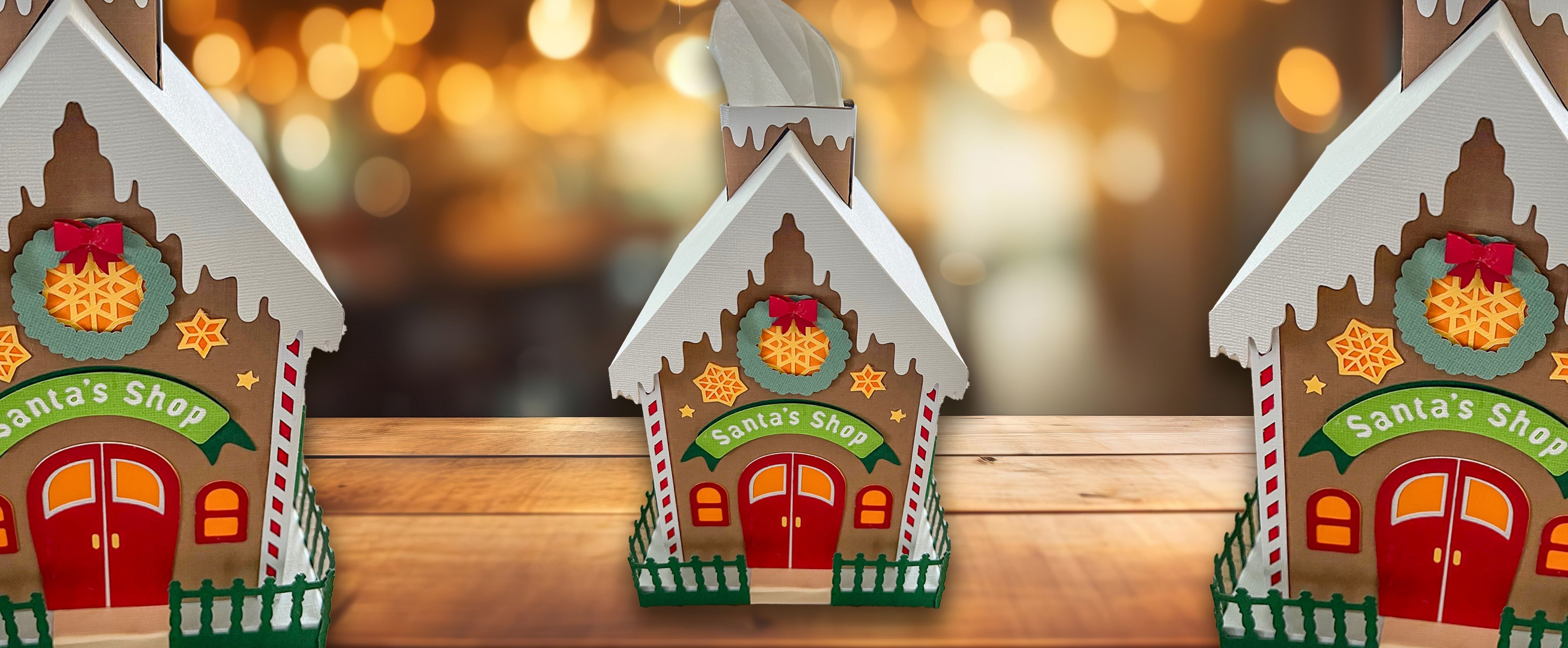 Papierhaus im Lebkuchenstil ‘Santa’s Shop’ mit Kranz, Fenstern und weihnachtlichen Details.