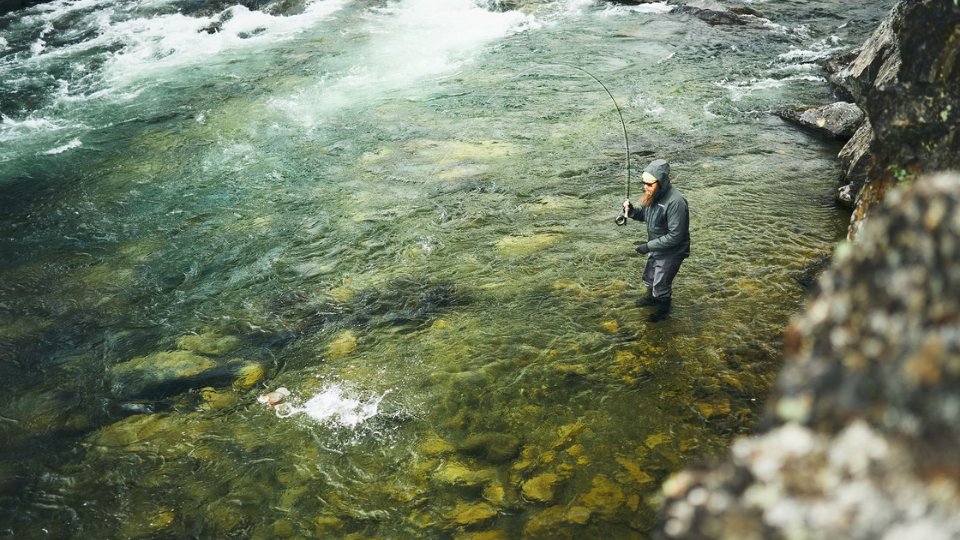 Ein Mann beim Fliegenfischen mitten in einem klaren Fluss mit der neuen Guideline Ausrüstung 2026.png