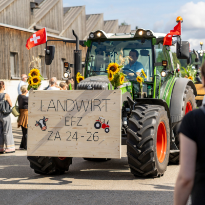 Ein mit Sonnenblumen und Schweizer Fahnen geschmückter Traktor mit einem Schild für die Landwirt-EFZ-Absolventen bei der Diplomfeier am Strickhof.png