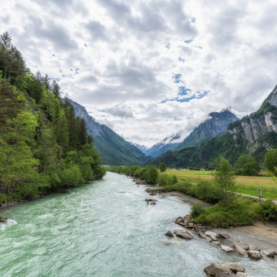 Das smaragdgrüne Wasser der Aare fliesst durch ein alpines Tal im Berner Oberland umgeben von steilen Felswänden und Wäldern.png