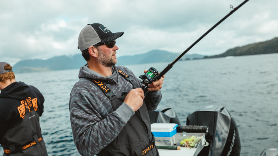 Angler in robuster Grundéns Angelbekleidung steht an einem nebligen See und fischt bei schlechtem Wetter.png