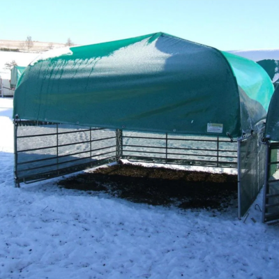 Grünes Weidezelt mit Panel-Gitterrahmen als Witterungsschutz für Tiere auf einer verschneiten Weide im Winter.png