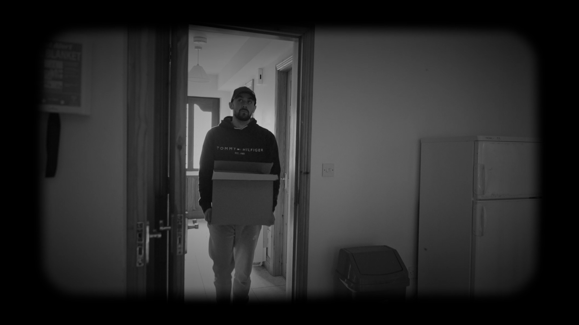Man carrying a box enters kitchen through a door