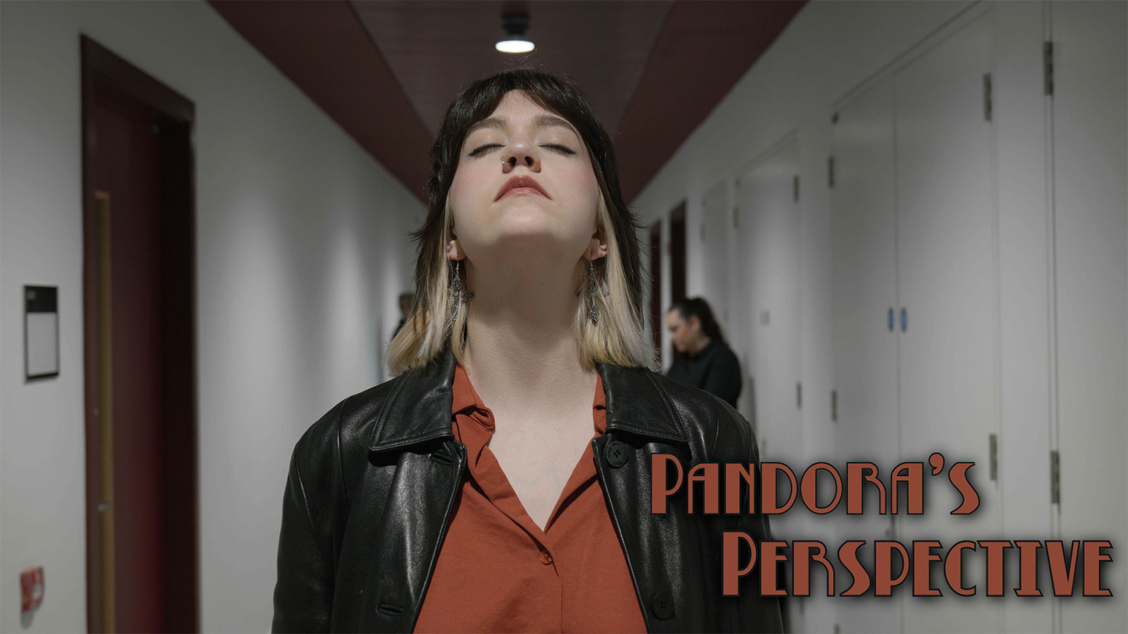 A young woman with dark hair and blonde ends stands in the center of a hallway with her eyes closed and head tilted upward. She wears a black leather jacket over a rust-colored shirt. The hallway is softly lit with white walls and doors on either side. The title “Pandora’s Perspective” appears in bold text in the bottom-right corner.