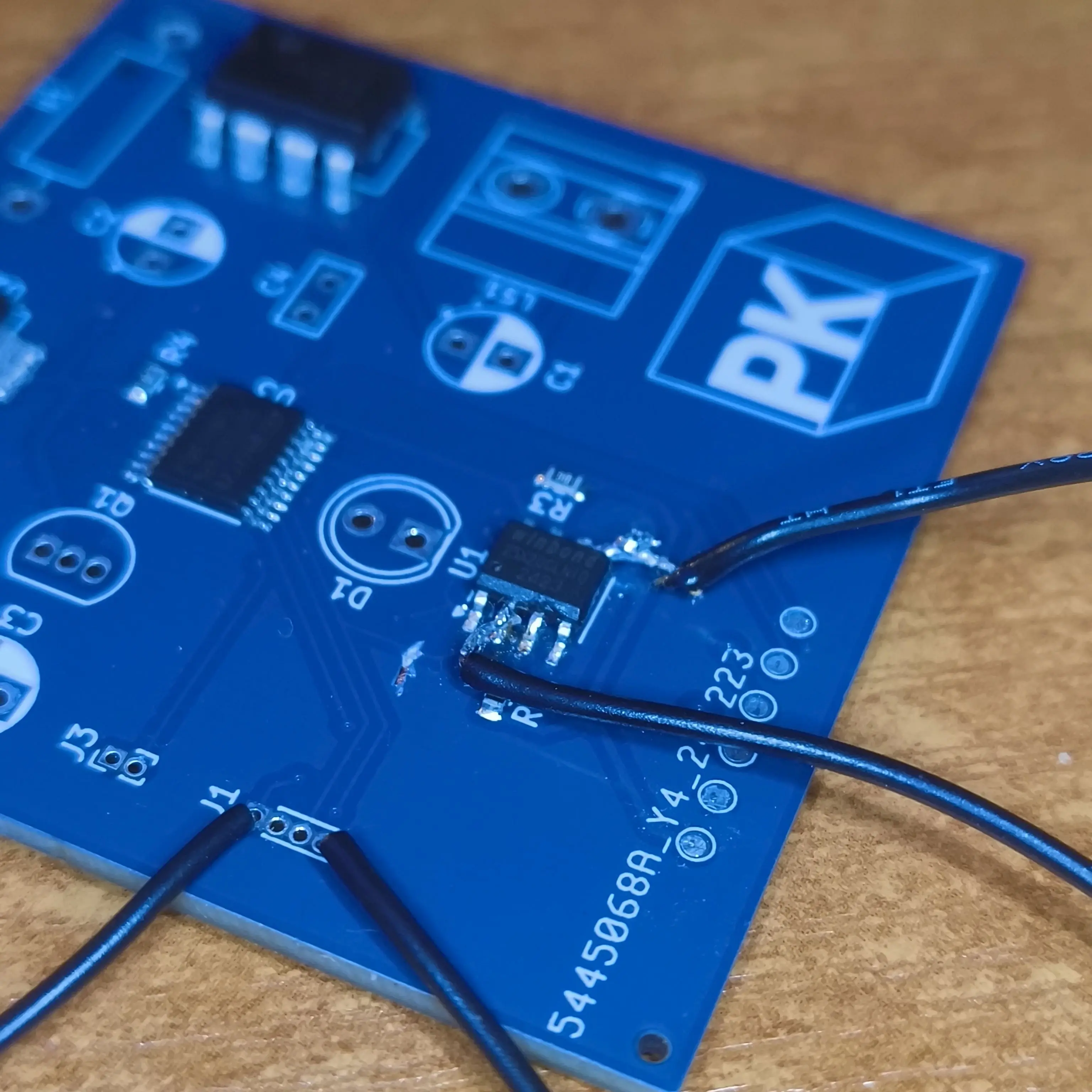 PCB board with two small wires soldered to the legs of an smd chip and a visibly cut trace