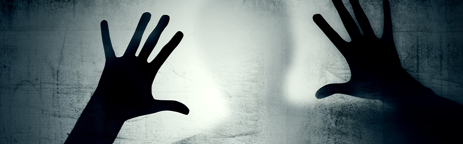 Silhouette einer Person, die ihre Hände gegen ein nebliges, beleuchtetes Glas oder eine Oberfläche drückt, wodurch ein geheimnisvoller Effekt entsteht.
