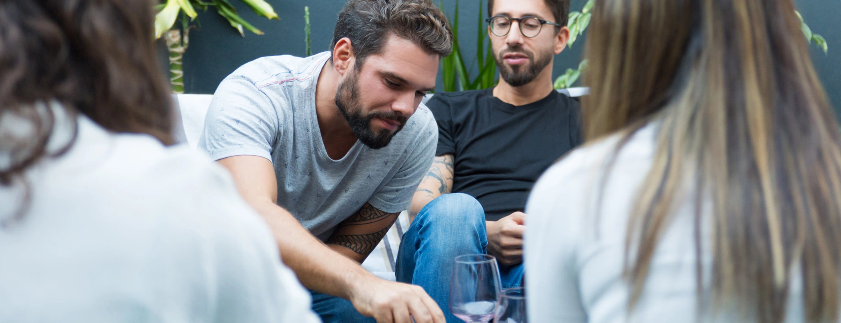 Vier Personen sitzen gemütlich bei Snacks und Wein zusammen