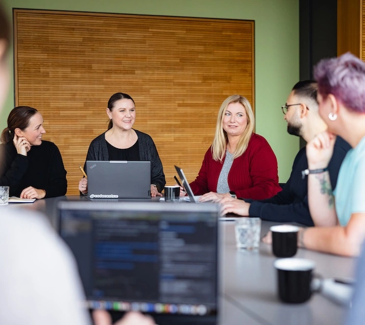 Fünf Kolleg*innen sitzen im Besprechungsraum an einem großen Tisch und dikutieren.
