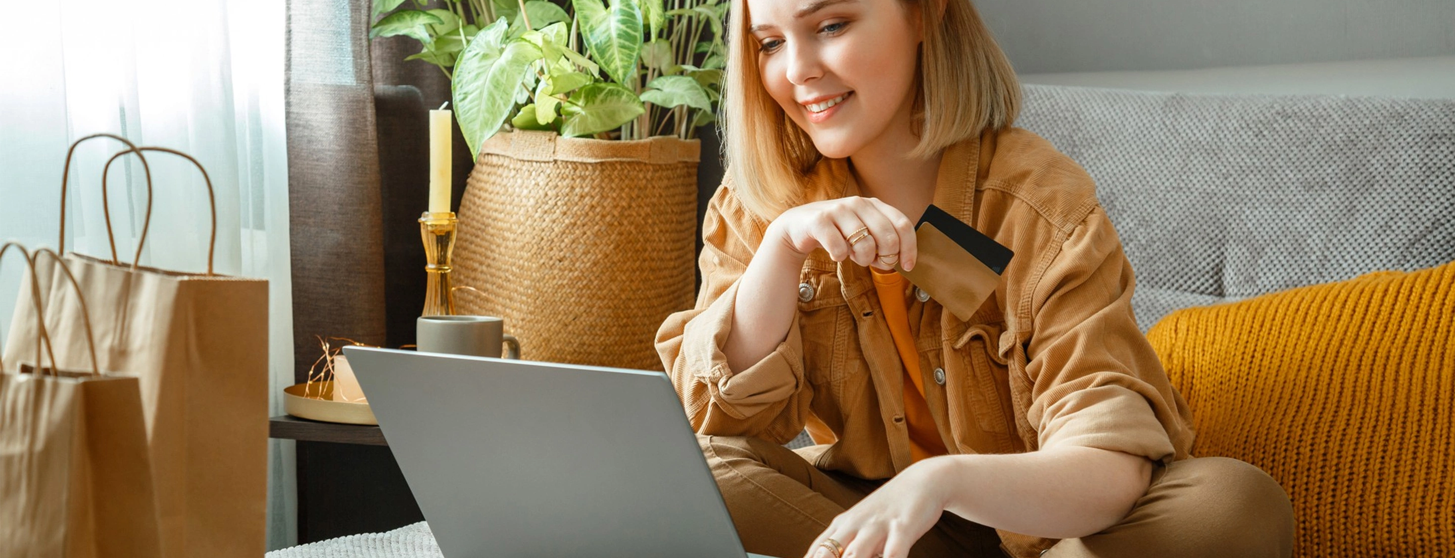 Eine Frau mit 2 Kreditkarten beim Home-Shopping am Notebook.