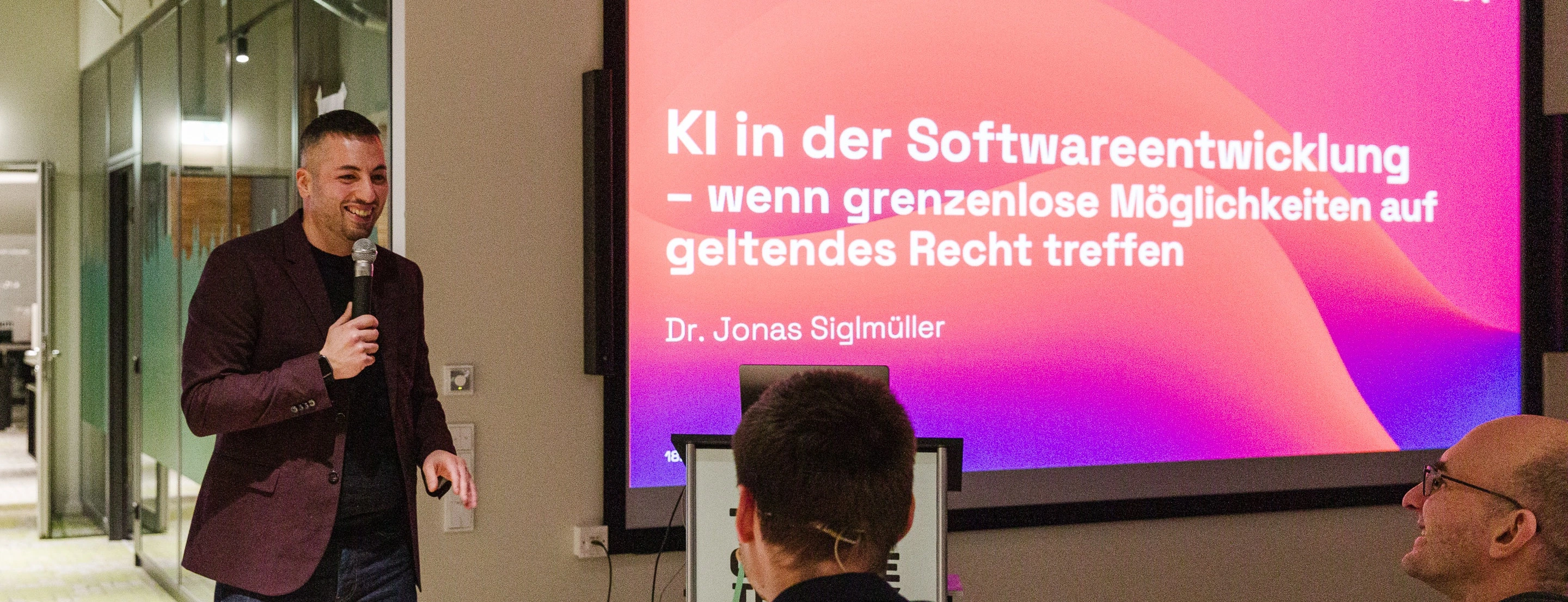codecentric Standortleiter Ali begrüßt die Gäste, im Hintergrund ist bereits die Titelfolie der Keynote.