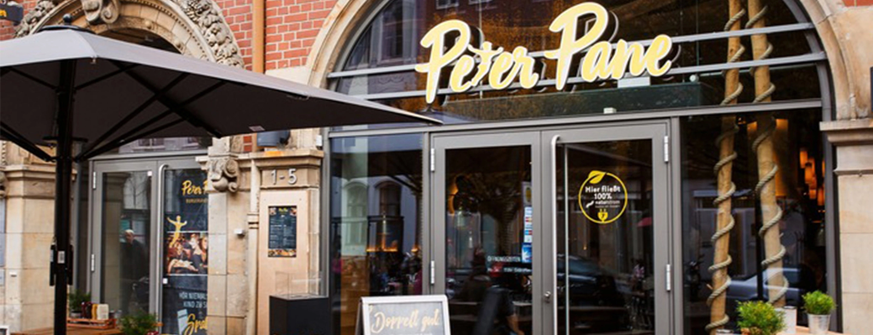 Ein Peter Pane Restaurant von außen aufgenommen, mit großer Glasfront und Schriftzug über der Tür.