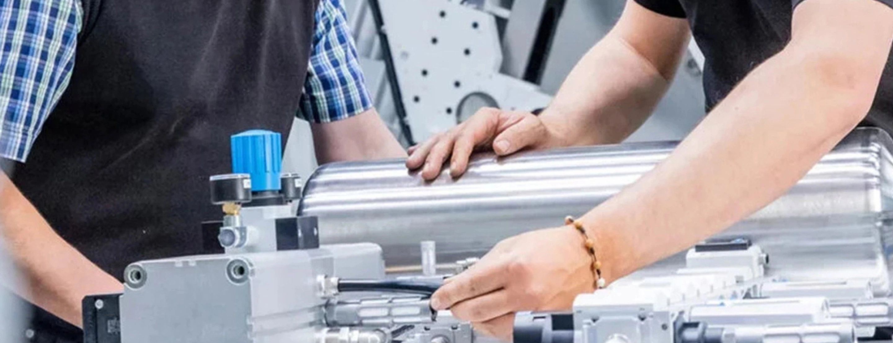 2 Personen, die an einer industriellen Maschine arbeiten.