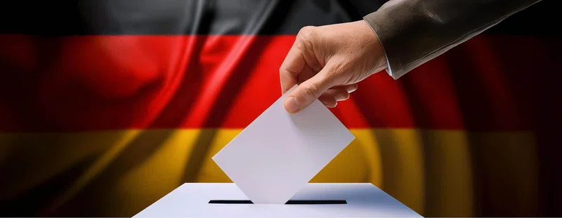 German flag behind a voter and a voting box