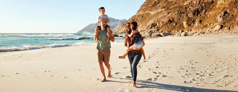 Family on holidays walking along beach