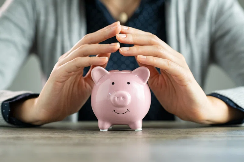 Pink piggy bank with hands hovering over 