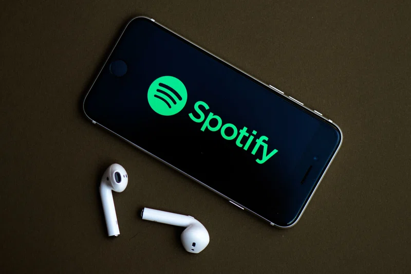 Spotify displaying on a smart phone, logo and air pods