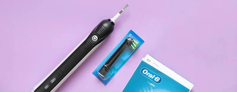Oral B electric toothbrush against a purple background