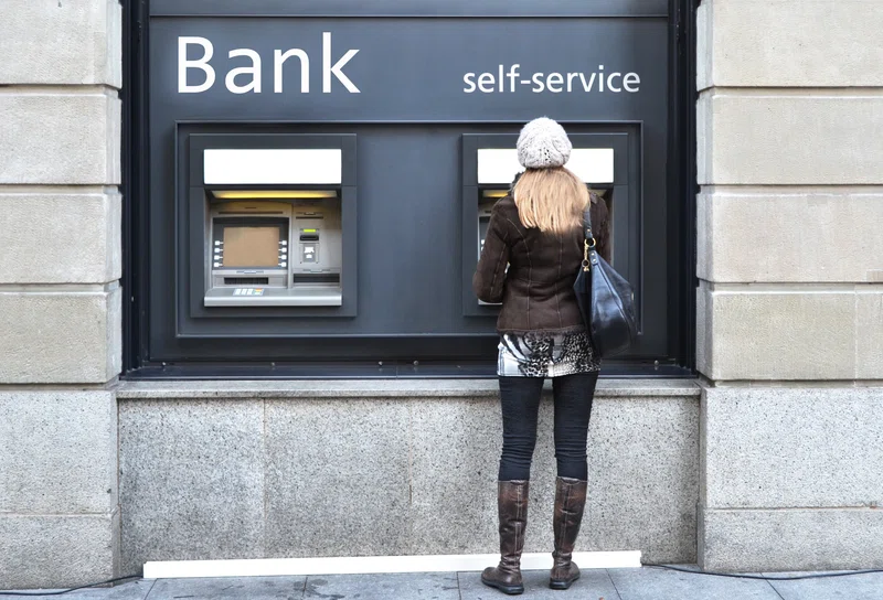 Lady standing at cash machine withdrawing money