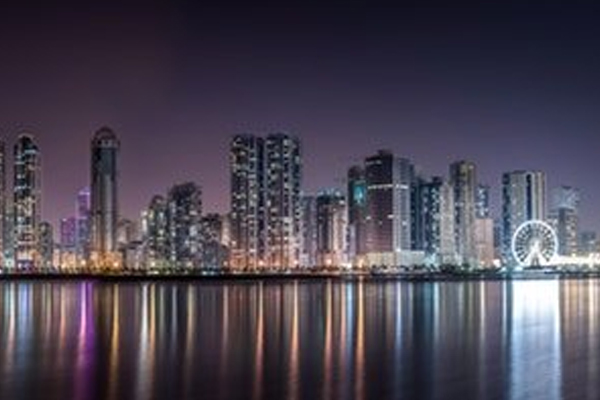 city landscape picture by the water at night with the buildings lit up.