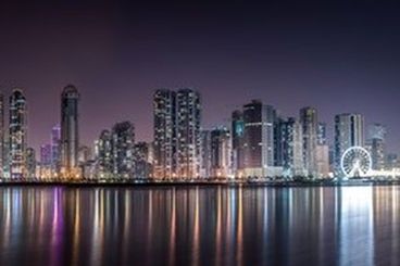 city landscape picture by the water at night with the buildings lit up.