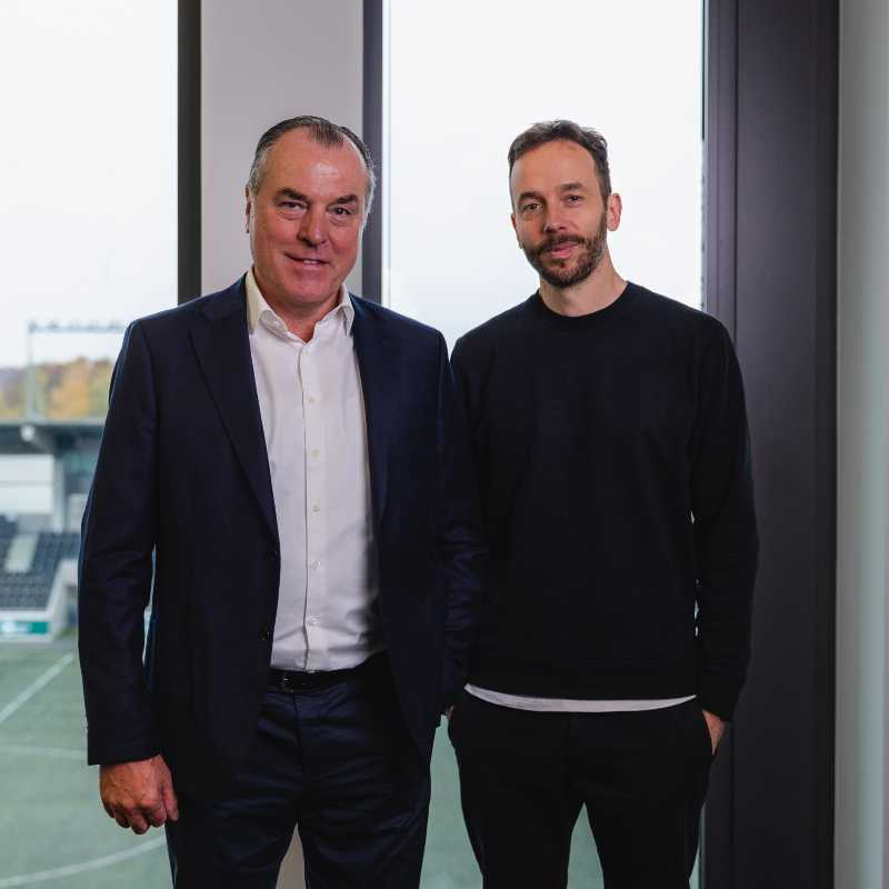 Clemens Tönnies und Philipp Westermeyer (v.l.) in der Premium-Food-Group-Zentrale in Rheda-Wiedenbrück. Im Hintergrund der firmeneigene Fußballplatz – mit Rasenheizung. Foto: OMR