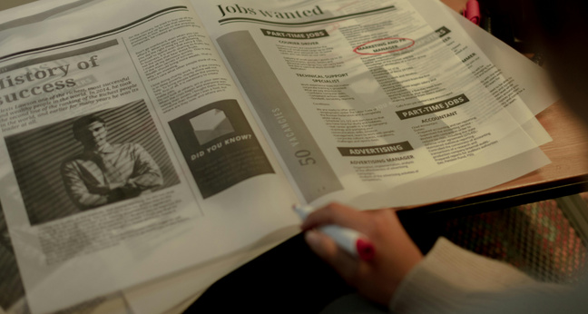 Zu sehen ist eine aufgeschlagene Zeitung in der Stellenausschreibungen inseriert sind. Dort wurde ein rot markiert.