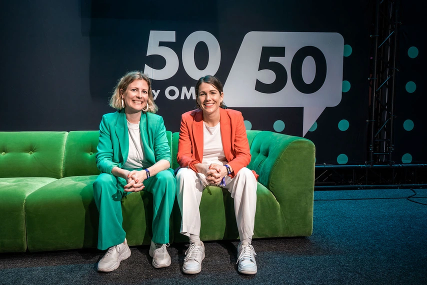 Zwei Frauen sitzen auf einer grünen Couch vor dem 5050-OMR-Logo – Bühnensetting eines Events für Gleichstellung und Gründerinnen.