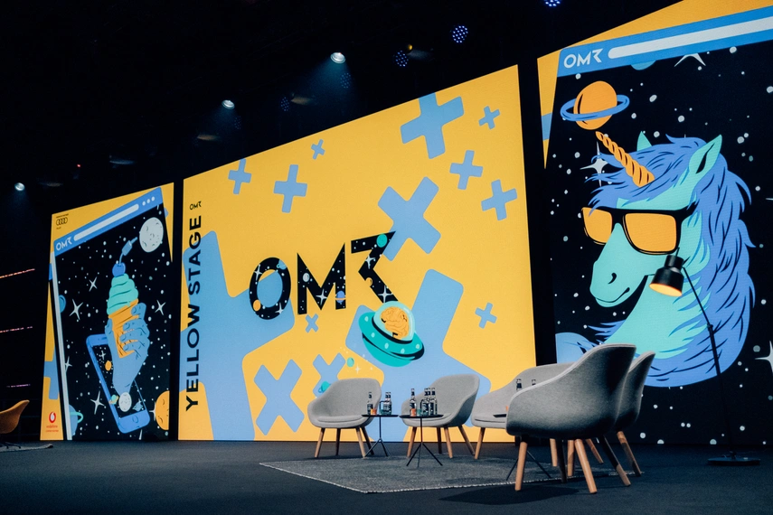 Blick auf die Yellow Stage beim OMR Festival mit leuchtend gelbem Bühnenbild, auffälliger Einhorn-Illustration und moderner Sitzgruppe – eine der zentralen Festivalbühnen für Keynotes und HR-Formate.