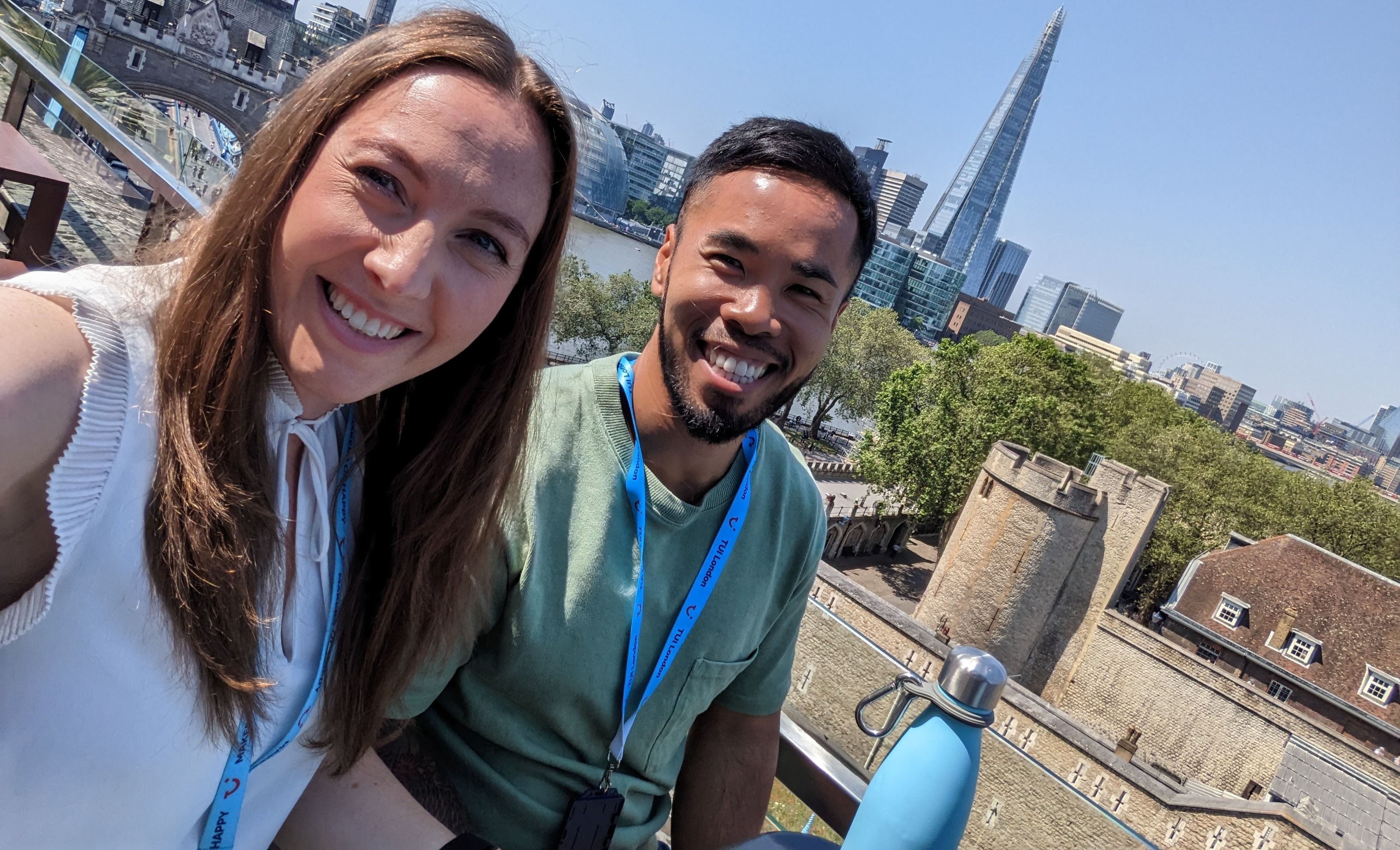 Zwei lächelnde Personen mit TUI-Ausweisen machen ein Selfie auf einer Dachterrasse mit Blick über London; im Hintergrund Tower Bridge und The Shard.