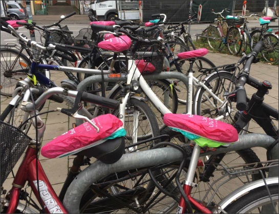 Fahrräder mit Sattelschonern in Hamburg. Im Vordergrund: Sattelschoner von Deliveroo, mit Schutzbezügen von Foodora überdeckt